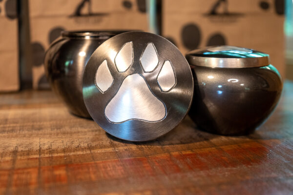 Brass Paw Print Jar. Rounded brass pot-shaped urn with single paw print on lid. Top threaded lid to ensure secure closure. 3 sizes available.